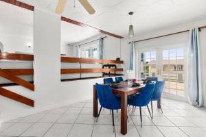 a dining room with a wooden table and blue chairs at Beautiful Oistins Home Away From Home in Christ Church