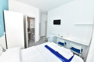 a white room with a bed and two blue chairs at A San Lazzaro Rooms in San Lazzaro di Savena