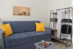 - un canapé bleu avec des oreillers jaunes dans le salon dans l'établissement Location Tame, à Douai