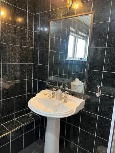 a black tiled bathroom with a sink and a mirror at Tudor House - 6 guests -Off street parking -Quiet location - Secure Garden in Pemberton