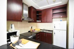 a kitchen with wooden cabinets and a white refrigerator at Amazing Dubai Studio in Dubai