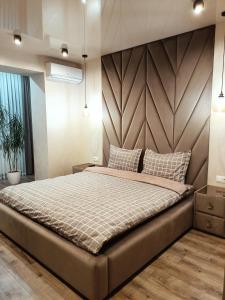 1 dormitorio con 1 cama grande y cabecero de madera en Вишуканий 1к люкс!, en Khmelʼnytsʼkyy