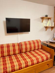 a living room with a couch with a television on the wall at Monolocale la terrazza sulla neve-Cervinia in Breuil-Cervinia