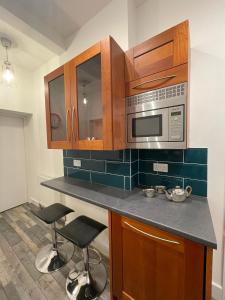 a kitchen with a counter with a microwave and stools at The Old Station, Station House, Snettisham Norfolk in Snettisham