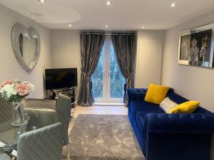 a living room with a blue couch and a tv at The Penthouse - Luxury 2 Bed Apartment in Skegness