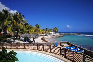 a resort with a pool and a beach with palm trees at Plaisir Caraïbes in Belle-Allée