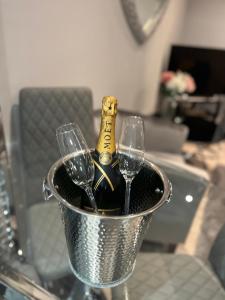 The Penthouse - Luxury 2 Bed Apartment في سكيجنيس: دلو مع زجاجة من الشمبانيا وكأسين من النبيذ