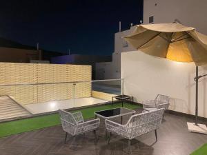 un patio con mesa, sillas y sombrilla en فلل اسوار الوسام لبيوت العطلات en Taif