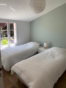 twee bedden in een kamer met twee ramen bij Maison Noirmoutrine agréable de 3 chambres avec grand jardin in Le Grand Vieil