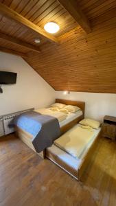 two beds in a room with a wooden ceiling at Guest House Alpha Ski Camp in Jahorina