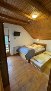 Duas camas num quarto com tecto em madeira em Guest House Alpha Ski Camp em Jahorina