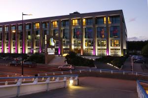 a large building with cars parked in front of it at Hotel Spa Le Pasino in Le Havre