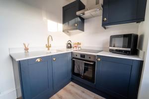 a kitchen with blue cabinets and a microwave at No 2 at Albion Terrace in Bath