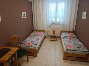 Cette chambre comprend 2 lits, une table et une fenêtre. dans l'établissement Penzion Kelčany u Kyjova, à Kelčany
