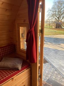 a small bed in a wooden cabin with a window at Schlaffässer auf dem Krügele Hof in Murr