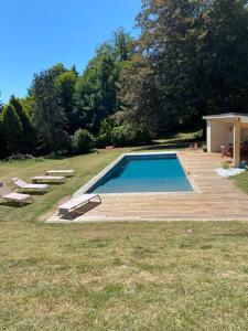 uma piscina num quintal com um deque de madeira em Maison chaleureuse avec piscine 