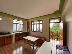 a kitchen with a table and some windows and a table at Aari INN Homestay in Aritar