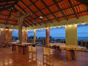 een restaurant met houten tafels, stoelen en ramen bij Nopalero Suites Hostel in Puerto Escondido