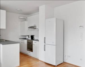 a white kitchen with white appliances and wooden floors at VIC Apartment in Vienna