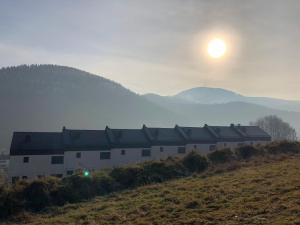 un bâtiment sur une colline avec le soleil dans le ciel dans l'établissement Cichy Strumyk z tarasem Słoneczna Góra, à Szczyrk