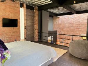 a bedroom with a bed and a tv on a brick wall at Mi Refugio San Angel in Mexico City