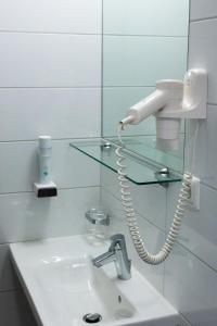 a bathroom with a sink and a phone on a mirror at Hotel Vinothek Schwarzer Adler in Ottensheim