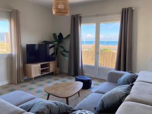 a living room with a couch and a tv at Joli appartement avec vue mer in Narbonne