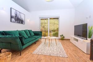 a living room with a green couch and a tv at Villa Marietta Equino in Donje Sitno