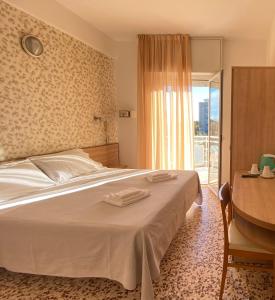 Hotel Ravello في ريميني: غرفة نوم بسرير ومكتب ونافذة
