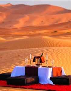 une table au milieu du désert avec des bougies dans l'établissement Luxury Local Camp, à Merzouga