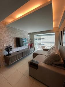uma sala de estar com um sofá e uma televisão de ecrã plano em Apartamento Confortável e Completo - JTR em Maceió
