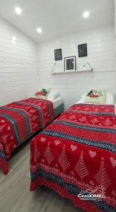 two beds in a room with red comforters at CzaDomki in Ustroń