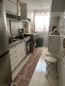 a kitchen with white cabinets and a sink and a chair at Apto com conforto que você precisa. in Goiânia