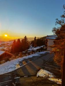 un aparcamiento cubierto de nieve con la puesta de sol en el fondo en Studio avec vue panoramique sur la montagne, en Font-Romeu-Odeillo-Via