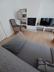 a living room with a gray couch and a tv at O 21 da Vila in Seia