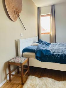 een slaapkamer met een bed, een raam en een kruk bij Zeehuis in Koksijde