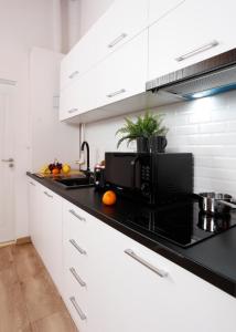 una cucina con mobili bianchi e un piano di lavoro nero di One Love Central Cottage a Bucarest Altre 10 foto