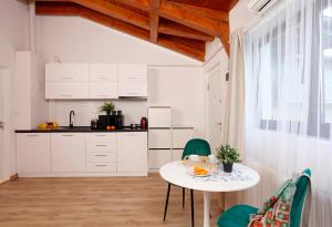 a kitchen with white cabinets and a table and chairs at One Love Central Cottage in Bucharest