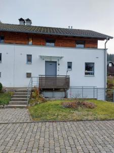 ein weißes Gebäude mit einer Veranda und einer Treppe davor in der Unterkunft Ferienhaus Ketterer Hinterzarten in Hinterzarten