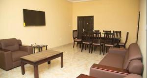 ein Wohnzimmer mit einem Sofa, einem Tisch und Stühlen in der Unterkunft Extended Stay in Adentan
