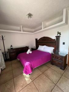 a bedroom with a large bed with a pink bedspread at Casa Lomas Grangelo in Atlixco