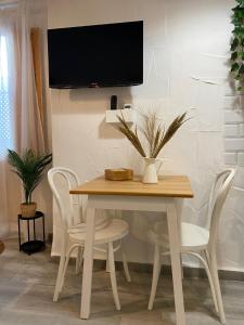 a dining room table with white chairs and a tv on a wall at Loft Xera - parking privado in Jerez de la Frontera