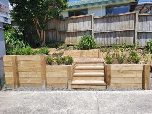 um jardim com degraus de madeira em frente a uma cerca em Pohutukawa Lodge by Orewa Beach em Orewa