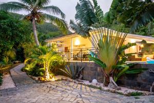 a house with palm trees and a stone walkway at Villa Fleur de Pirate in Orient Bay