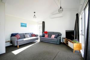 a living room with two couches and a tv at Opunake Break - Opunake Holiday Home in Opunake