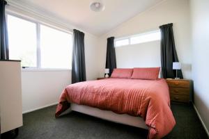 a bedroom with a large bed and two windows at Opunake Break - Opunake Holiday Home in Opunake