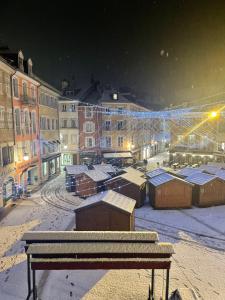 een uitzicht op een besneeuwde stad 's nachts met een bank bij L’appart chic gapençais in Gap