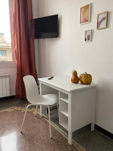 einen weißen Schreibtisch mit Stuhl und einen TV an der Wand in der Unterkunft CASA AMEDEO in Genua