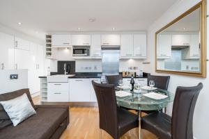 cocina y sala de estar con mesa de cristal y sillas en Camden Town Apartment, en Londres