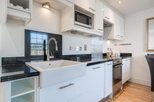 una cocina con armarios blancos y fregadero en Camden Town Apartment en Londres